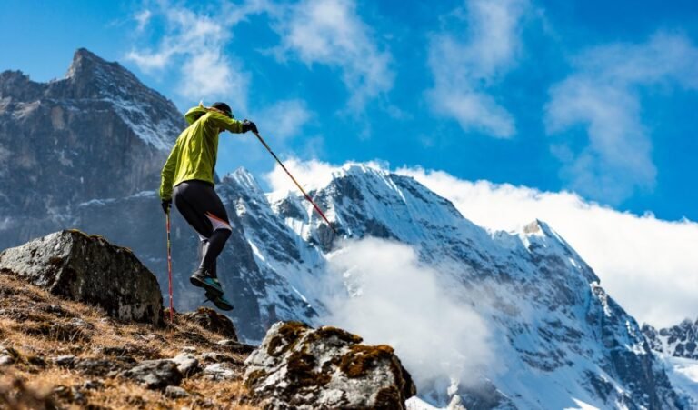 Trekker leaping across rocks in front of Himalayan peaks